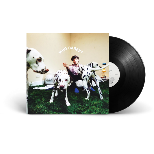 A vinyl record partially pulled from its album sleeve, showing the cover art of 'Who Cares?' with a man sitting between three Dalmatian dogs. The black vinyl disc is visible on the right